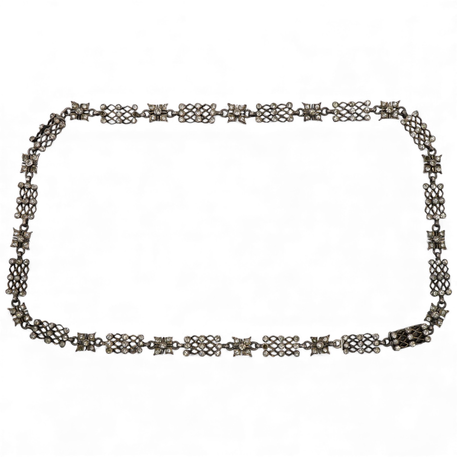 An early 20th century white metal and white paste set cluster necklace, each trellis style link mounted with nine paste stones, approx. 38cm.